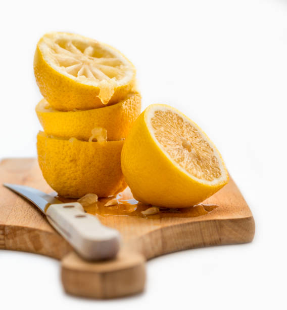 three squeezed lemons, cutting knife and board. One half, freshly cute lemon