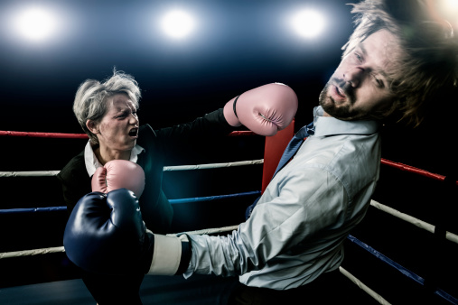 Businesswoman punching businessman in boxing fight