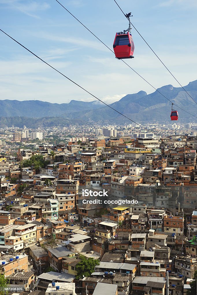 Rio de Janeiro Favela Slum with Red Cable Cars Red cable cars traveling in blue sky above Rio de Janeiro favela Complexo Alemao Rio de Janeiro Stock Photo