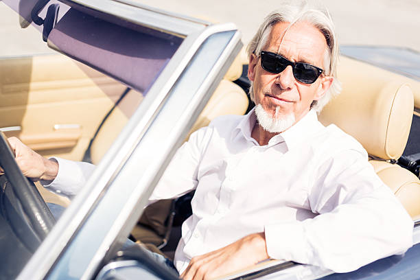 istock senior man driving a convertible classic car 487209796