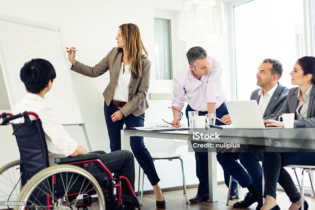 business team having a meeting business team having a meeting in a modern office. one man is sitting in a wheelchair. Whiteboard - Visual Aid Stock Photo