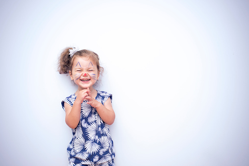 Portrait of attractive caucasian little child girl with blond curly hair and cute smile. Happy smiling child looking at camera - close-up, outdoors.