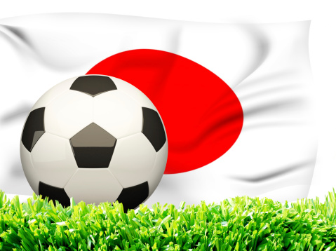 Flag of Japan with soccer ball over grass background