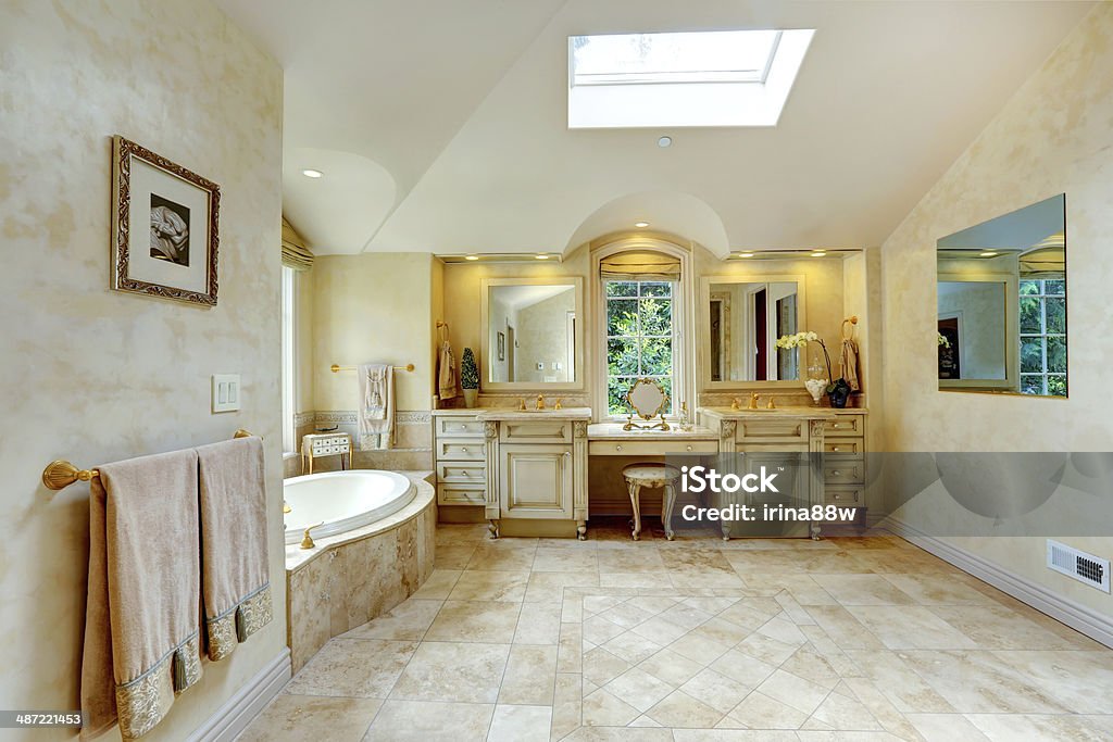 Luxury bathroom with antique vanity and cabinets Spacious luxury bathroom with high vaulted ceiling and velux window. View of antique old vanity with cabinets and bath tub Architect Stock Photo