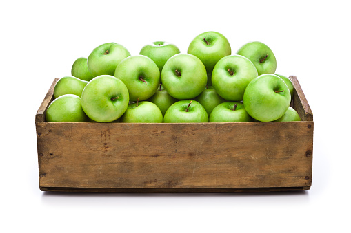 Front view of a wooden crate filled with fresh organic green apples sitting on white background. Predominant color is brown and green. DSRL studio photo taken with Canon EOS 5D Mk II and Canon EF 24-105mm f/4L IS USM Lens