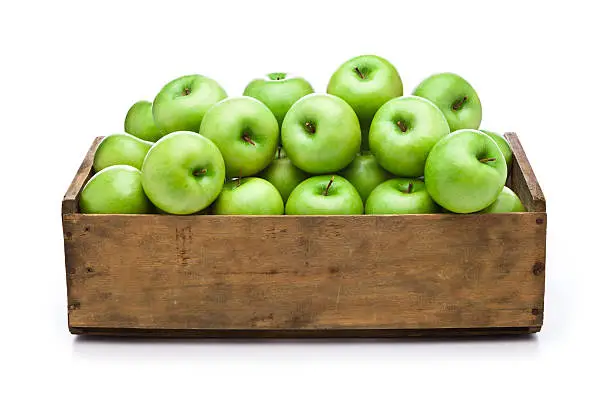 Front view of a wooden crate filled with fresh organic green apples sitting on white background. Predominant color is brown and green. DSRL studio photo taken with Canon EOS 5D Mk II and Canon EF 24-105mm f/4L IS USM Lens