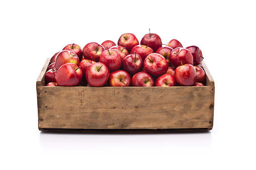 Front view of a wooden crate filled with fresh organic red apples sitting on white background. Predominant color is brown and red. DSRL studio photo taken with Canon EOS 5D Mk II and Canon EF 24-105mm f/4L IS USM Lens