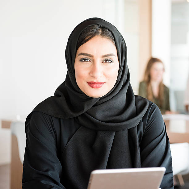 Young Arabic woman in modern office Arab businesswoman at work. Young Arab female in business office holding digital tablet. She is wearing traditinal Emirati Middle Eastern arab woman stock pictures, royalty-free photos & images