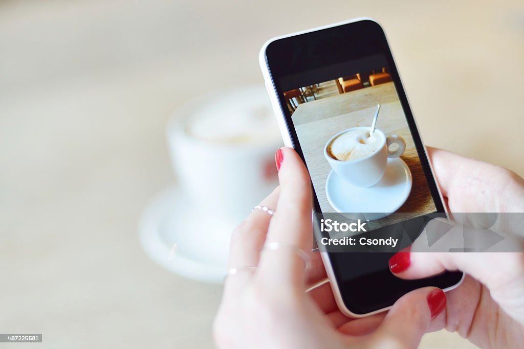 Smartphone taking picture from a coffee Young woman making picture from a coffee with smartphone. Mobile Phone Stock Photo