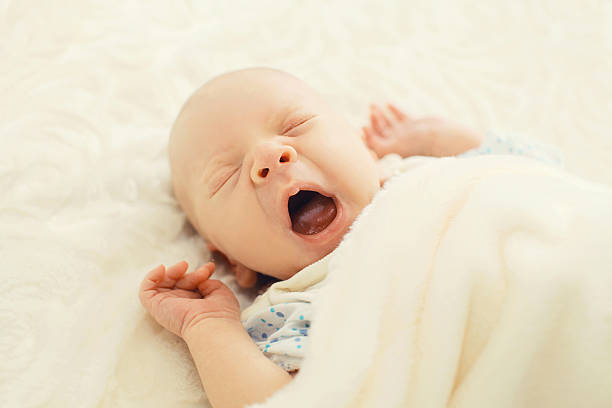 istock Sweet sleep infant lying and yawning on the bed 487228038