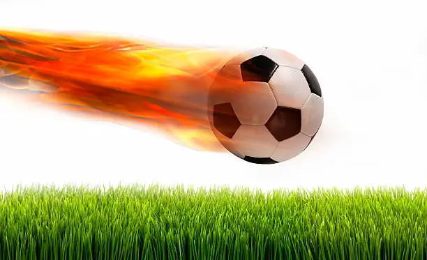 Smokin soccer ball on fire over green field.