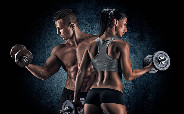 Athletic man and woman with a dumbells. Man and woman isolated on a dark background images of female bodybuilders stock pictures, royalty-free photos & images