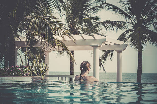 istock Woman Relaxing Inside Infinity Pool At Tropical Resort 487242928