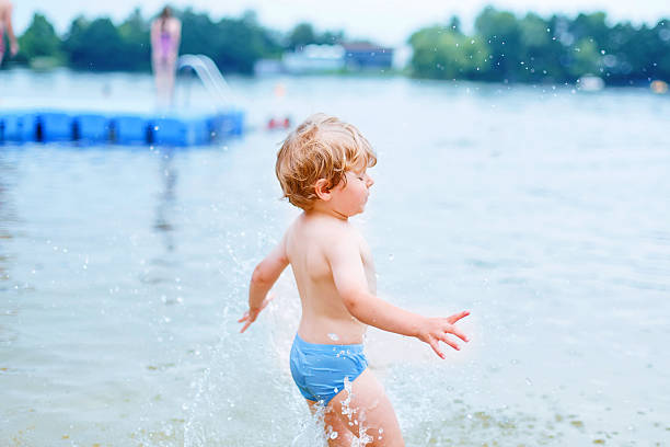 istock Little blond kid boy  taking bath in lake 487247018