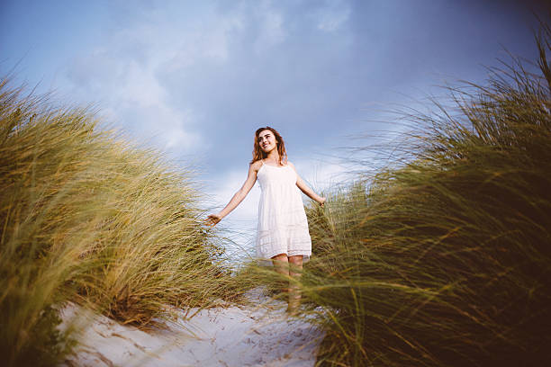 istock Girl walking through beach dunes at sunset 487251137