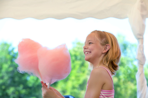 Cute young girl is excited about eating cotton candy.  RM