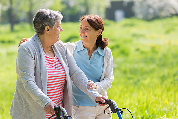 istock caregiver and senior woman with walking frame 487253151