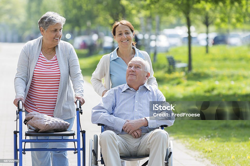 caregiver and senior couple with wheelchair and walking frame Assistance living – caregiver and senior couple with wheelchair and walking frame A Helping Hand Stock Photo
