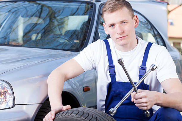 istock Mechanic with car wheel unscrewing key 487256189