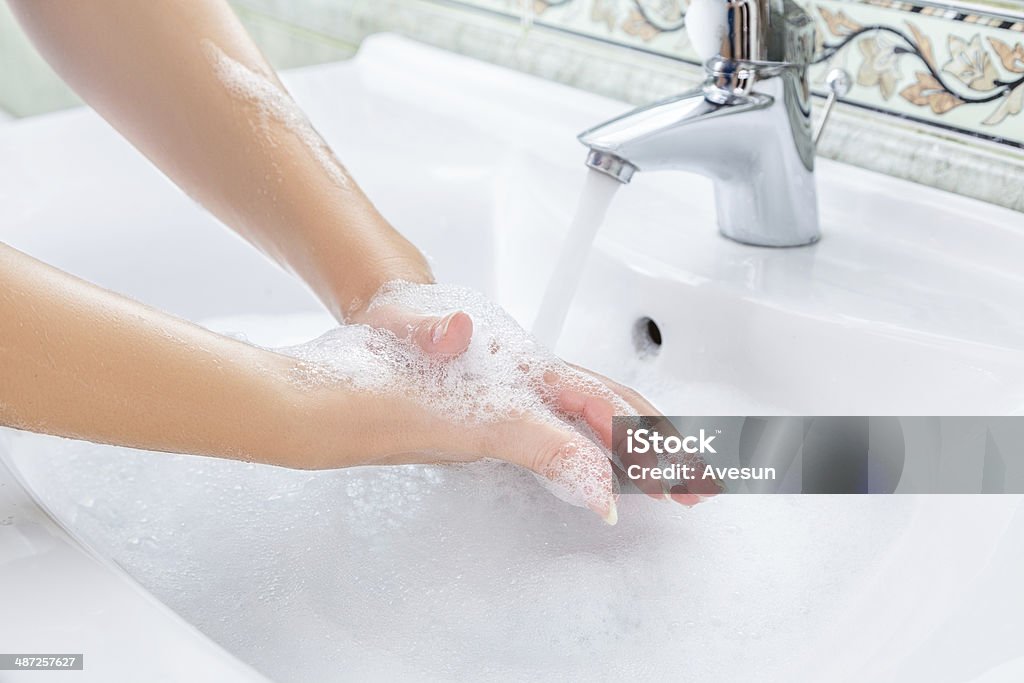 Woman washing hands Young woman washing hands with soap in sink Adult Stock Photo