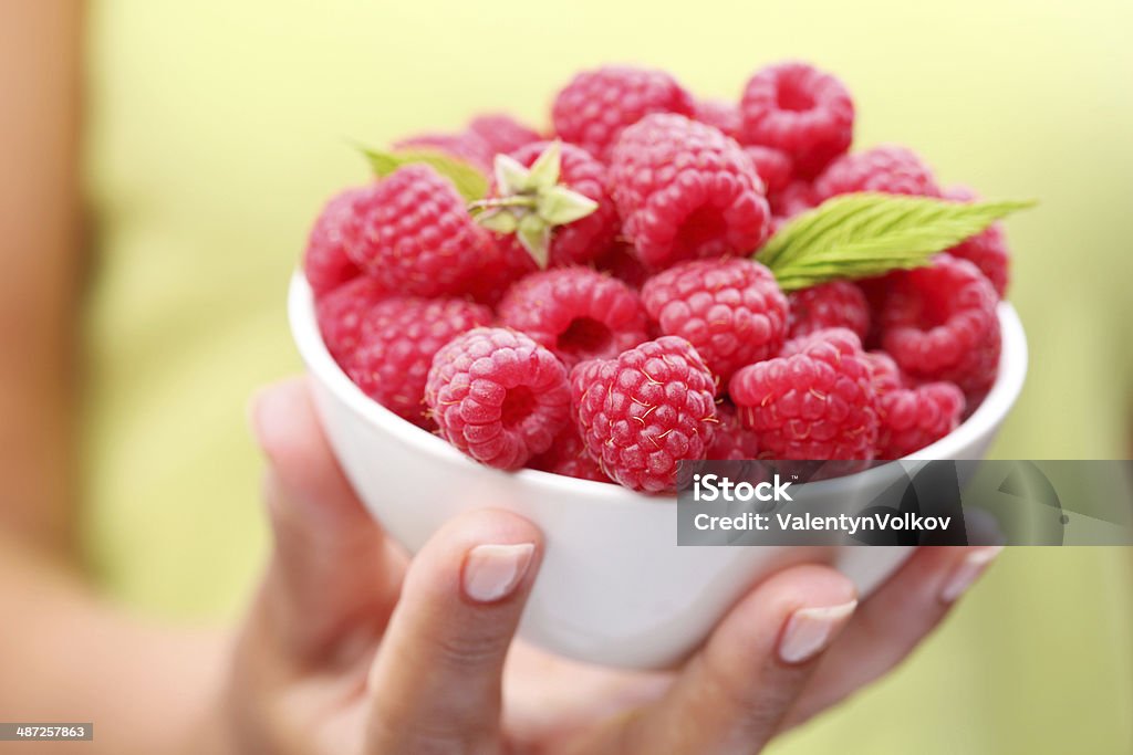 Crockery with raspberries in woman hand. Small crockery with raspberries in woman hand. Adult Stock Photo