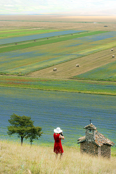 photographe portant robe rouge abd chapeau blanc de castelluccio, italie - natural landmark outdoors vertical saturated color photos et images de collection