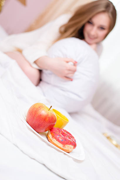 istock Young pretty woman covered with pillow having  breakfast in bed 487263512