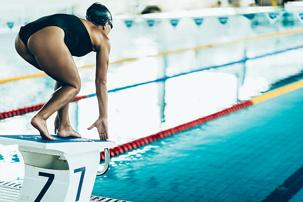 Swimmer on starting block Swimmer on starting block, in position, ready to start one piece swimsuit photos stock pictures, royalty-free photos & images
