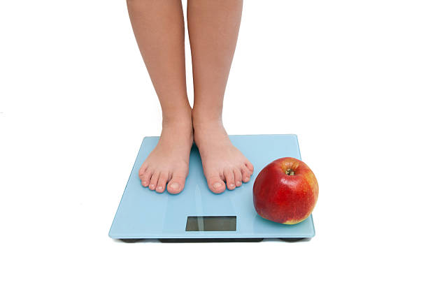 istock Pair of female legs standing on scale 487272391