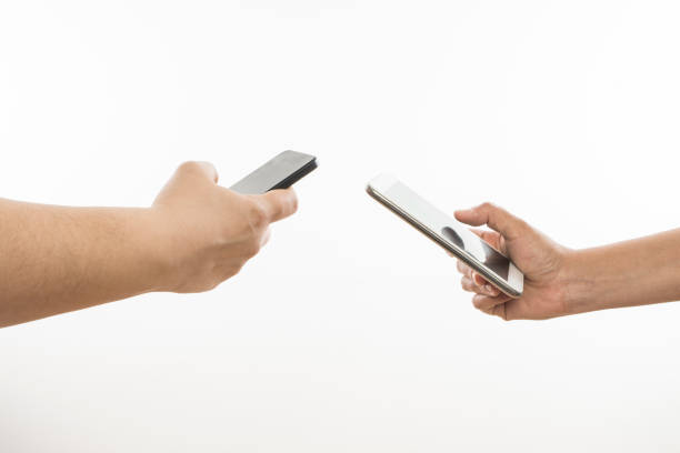 dos manos sosteniendo los teléfonos inteligentes conectados - standing digital tablet couple love fotografías e imágenes de stock