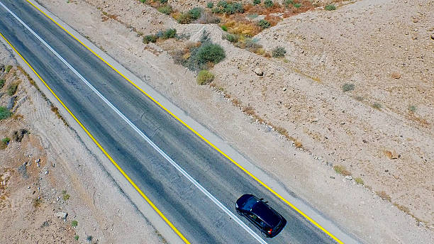 istock Black car moving along desert road. Aerial view 487295138