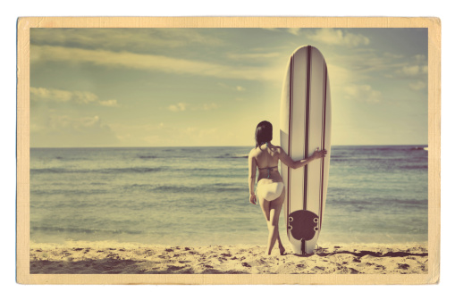 A Retro 40s-50s style antique postcard with a surfer on a tropical beach.