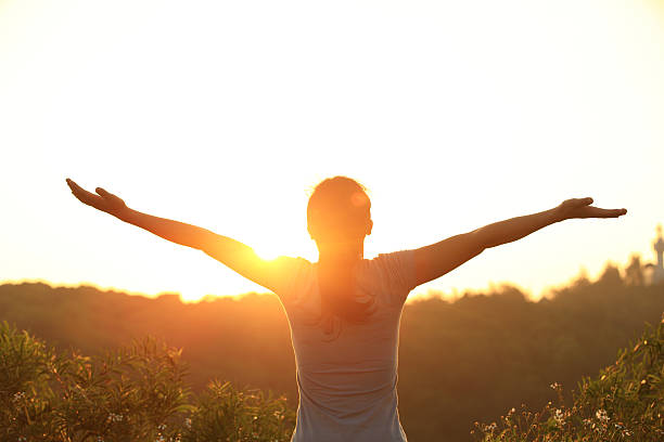 free woman open arms to sunrise