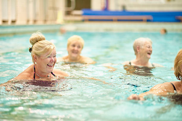 istock senior ladies having fun in pool 487300450