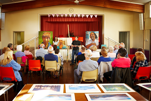 Art lecturer explaining painting techniques to seniors people attending the painting training courses