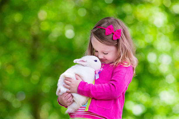 istock Little girl playing with rabbit 487300650