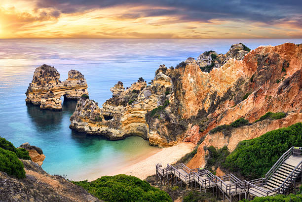 Sunrise at Camilo Beach, Lagos, Portugal The beautiful Camilo Beach in Lagos, Portugal, with its magnificent cliffs and the blue ocean colorfully lit at sunrise algarve stock pictures, royalty-free photos & images