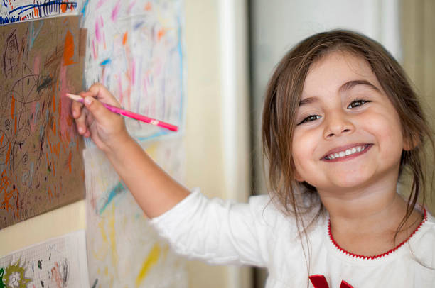 A little girl painting pictures in her room