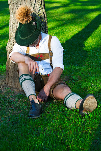 istock bavarian man sitting by a tree and sleeps 487316978