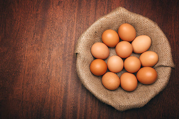 Brown Eggs in Burlap Brown eggs in a bulap lined basket on a dark brown wood table with copy space free range stock pictures, royalty-free photos & images