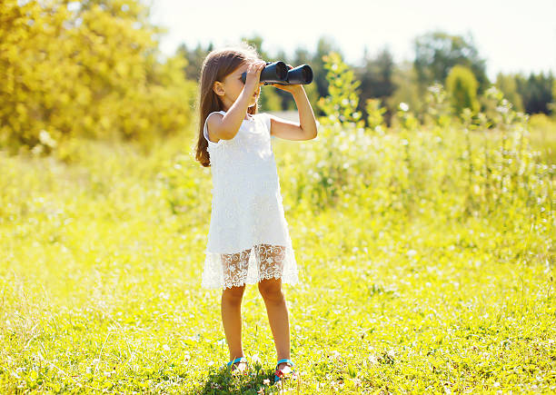 istock Little girl looks in binoculars sunny summer 487320508