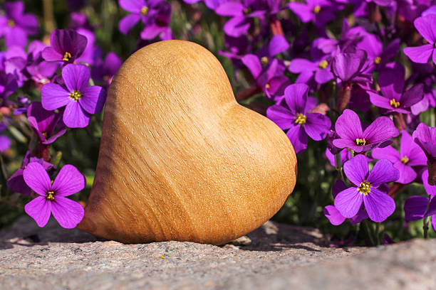 Stone with heart shape in a pale green bowl on a rustic wood surface. Directly above. Copy space.