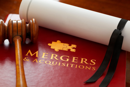 Red leather Mergers and Acquisitions Law Book with a gold embossed jigsaw piece logo and text, with a blank legal document and a judge’s gavel.