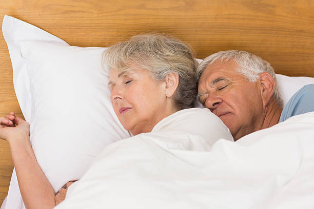 senior couple dormant dans un lit - couple affectionate relaxation high angle view photos et images de collection