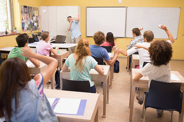 istock Students throwing paper balls on teacher 487327499