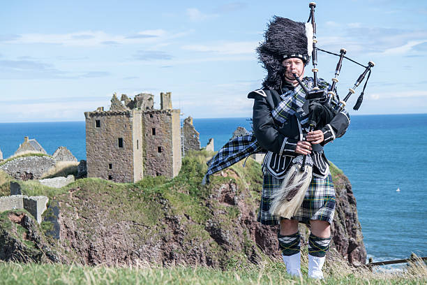 Traditional scottish bagpiper at Dunnottar Castle Traditional scottish bagpiper in full dress code at Dunnottar Castle scotland stock pictures, royalty-free photos & images