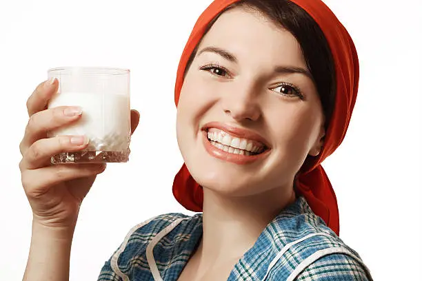 young girl in a red scarf holding a glass with milk and smiling