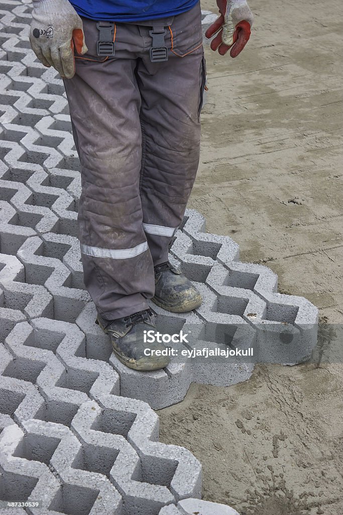 worker paving new parking places 8 Worker paving new parking places, concrete grid pavers can be filled with soil for grass growth or aggregate for drainage applications. Adult Stock Photo