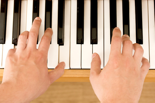 Close up on male hands playing piano at music lesson