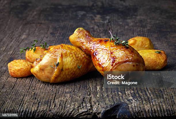 Roasted Chicken Legs And Potatoes On Wooden Cutting Board Stock Photo - Download Image Now